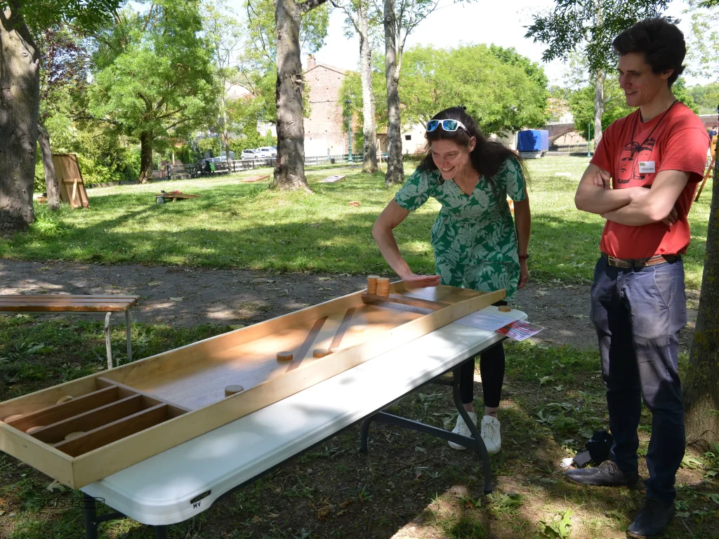 Votre serviteur, Alexandre Sahuguède, explique le billard hollandais à une femme lors d'une après-midi jeux en bois à Montesquieu-Volvestre en 2025.