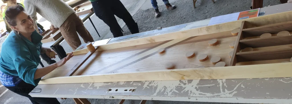 Une jeune femme joue avec beaucoup de plaisir au billard hollandais lors d'une animation de jeux en bois à la ressourcerie 09 en Ariège en 2023.