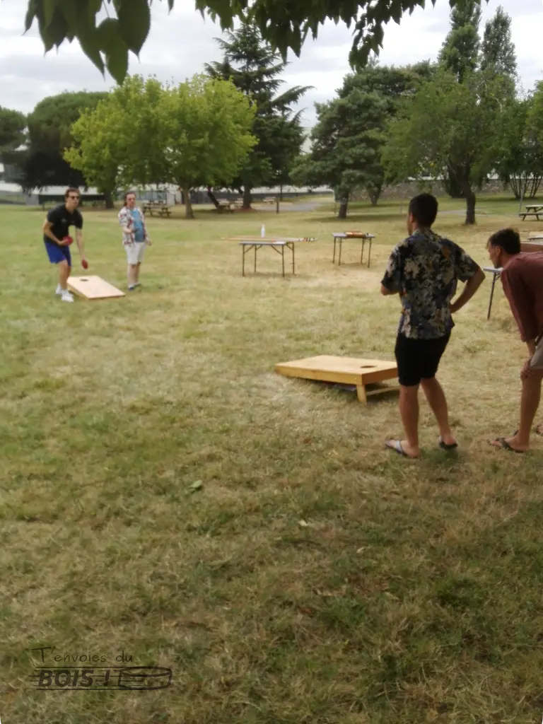 Un groupe de quatre amis jouent ensemble au cornhole. Ce jeu de lancer américain est l'idéal pour un moment convivial en extérieur.