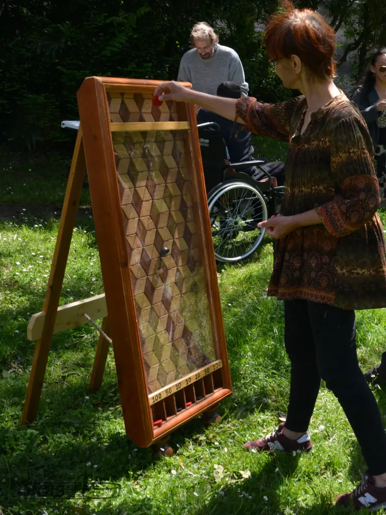 Une femme est captivée par les palets dégringolant le long du jeu du fakir, célèbre jeu en bois qui est passé dans l'émission télévisée le juste prix.