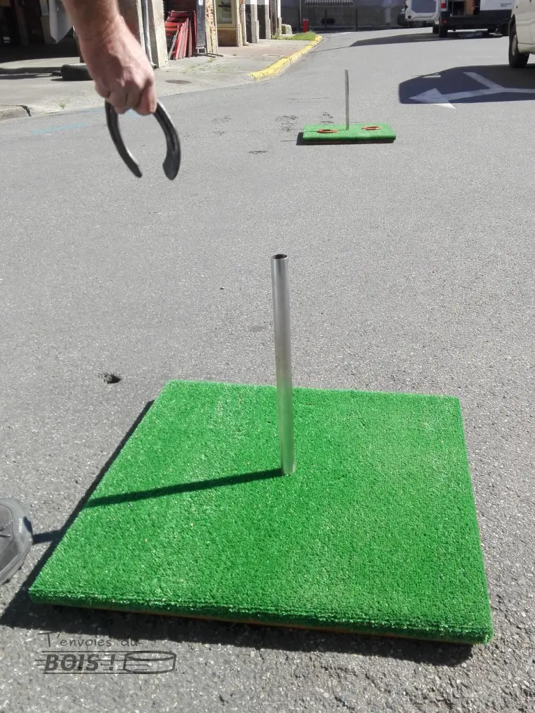 Un joueur s'apprête à lancer un fer à cheval sur ce jeu du fer à cheval fabriqué avec du bois de récupération.
