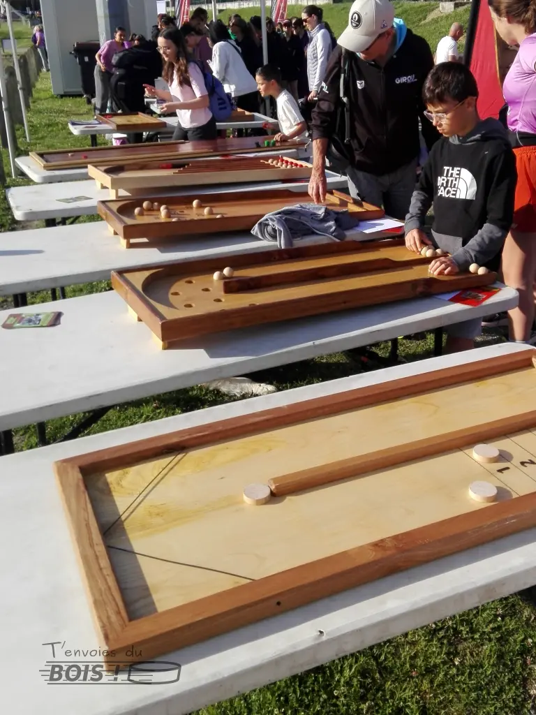 Plusieurs jeux en bois sont alignés lors de la course féminine Elle's run pour toutes en 2025. Sont visibles le billard à rebonds, le double chinois, le billard japonais, le billard aérobille et le jeu de galets.