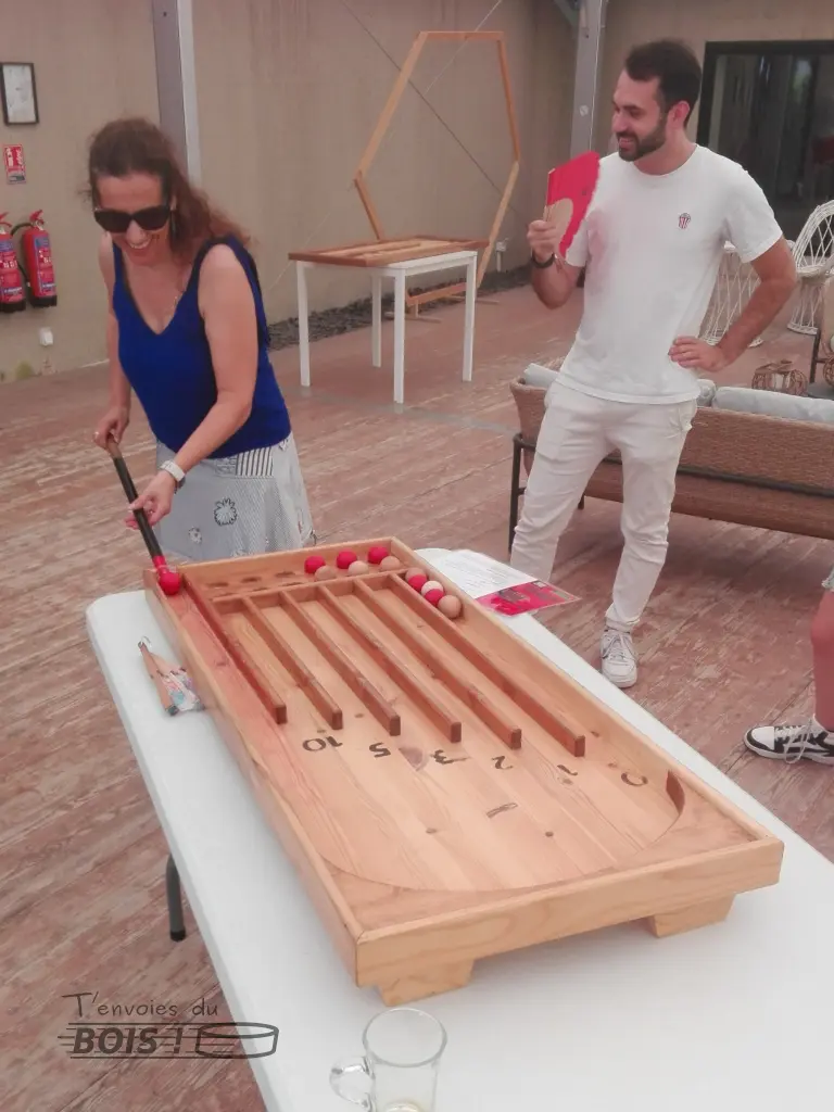 Une femme et un homme jouent au billard aérobille lors d'une journée de cohésion d'entreprise. Tout le monde est souriant. Photo prise en 2025.