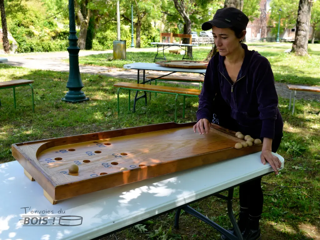 Une jeune femme joue au billard japonais dans une ambiance printanière. Elle a déjà marqué 30 points. Photo prise lors de l'après-midi jeux en bois à Montesquieu-Volvestre en 2025.