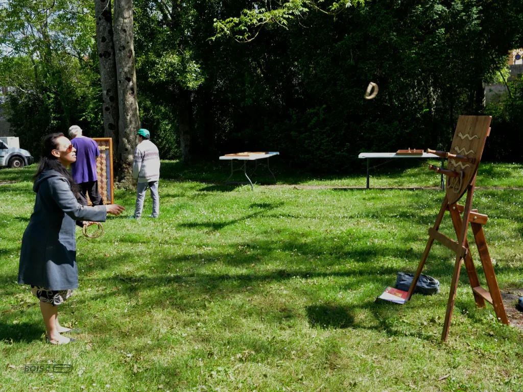 Une femme en plein lancer lors d'une partie de lancer d'anneau. Retrouvez d'autres jeux de lancer comme celui-ci près de Toulouse. Photo prise lors d'une après-midi jeux en bois à Montesquieu-Volvestre.