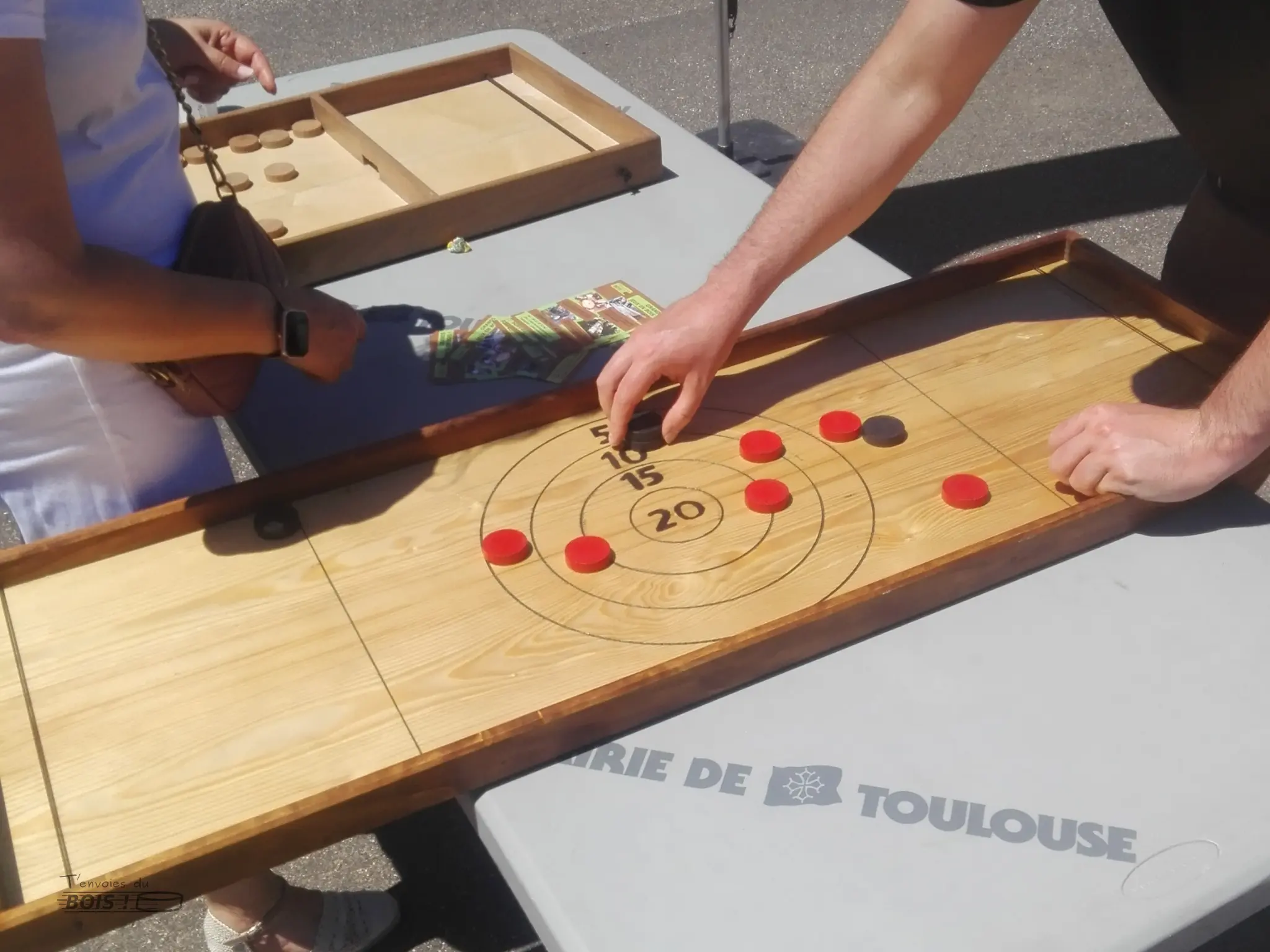 Le passe-trappe et le tir sur cible sont deux jeux en bois avec des palets. Photo prise lors de l'inauguration de l'allée Pierre de Serre de Saint-Roman à Toulouse en juin 2025.