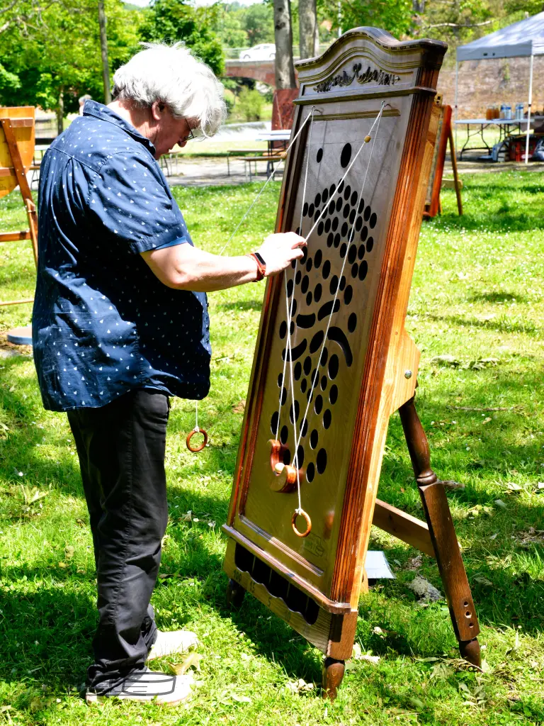 Un homme, Thierry Sahuguède, découvre le travail de son fils, votre serviteur, Alexandre Sahuguède. Il tente une partie de jeu du gruyère. Photo prise lors d'une après-midi jeux en bois à Montesquieu-Volvestre en 2025.