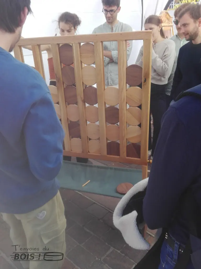 Un groupe de jeunes gens autour d'une partie de puissance 4 géant. La tension est à son comble. Photo prise lors du Festival Toulouse Innovante et Durable sur la place du Capitole à Toulouse en 2025.