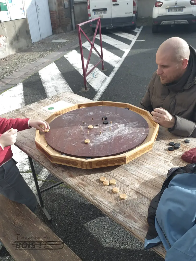 Une partie de crokinole, ce célèbre jeu canadien en bois, lors d'un marché de Noël à Lombez. Photo prise en 2025.