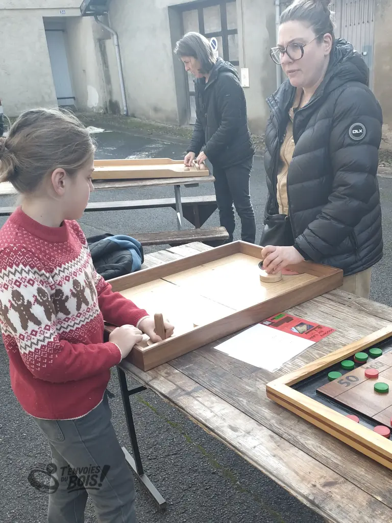 Un garçon joue avec sa mère au hockey sur table lors d'un marché de Noël. Photo prise à Lombez en décembre 2025.