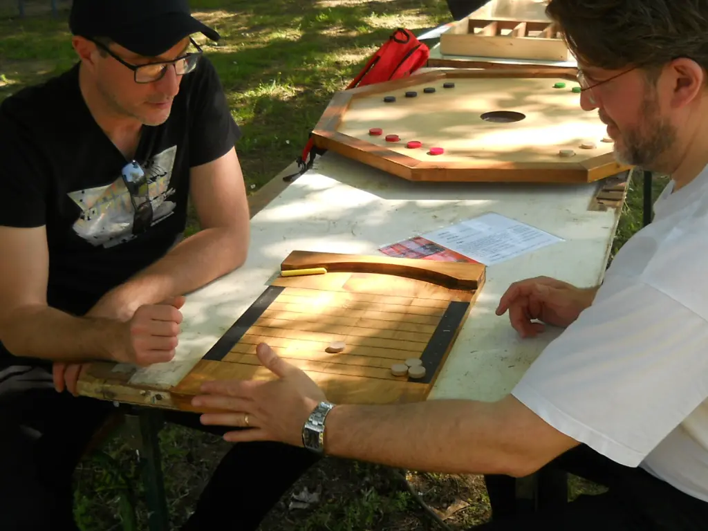 Deux hommes jouent au palet anglais par une belle après-midi ensoleillée. Photo capturée lors de l'après-midi jeux en bois à Montesquieu-Volvestre en 2024.