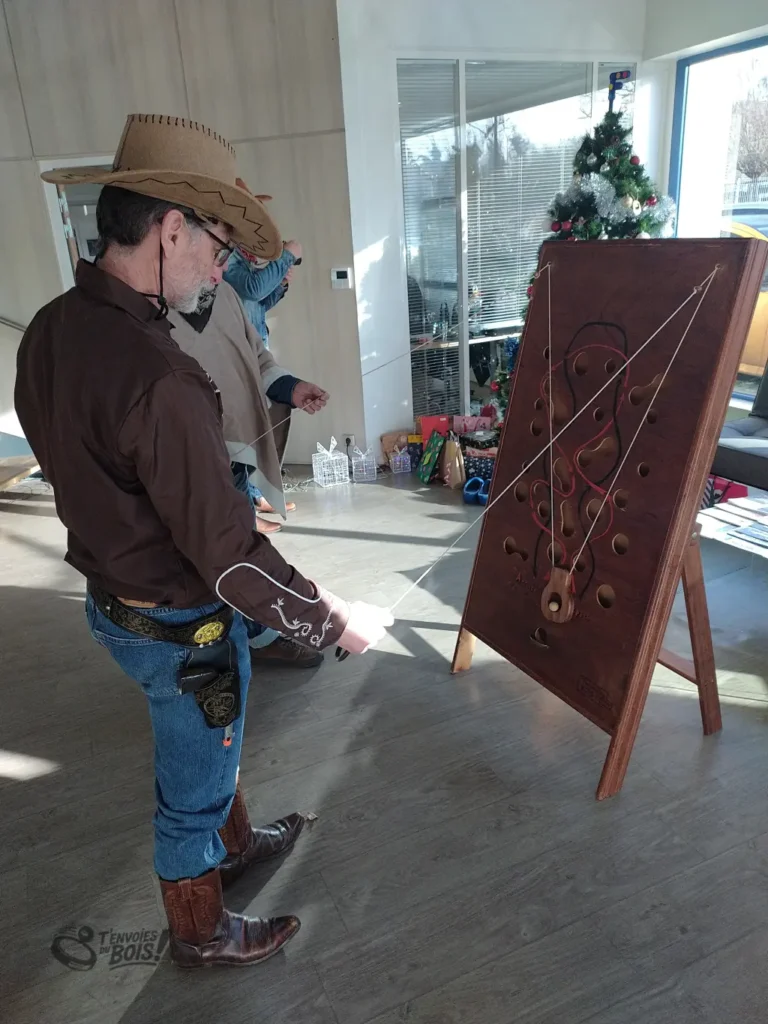 Un homme en costume de cow-boy joue au slalom géant. On peut voir un arbre de Noël en arrière-plan. Photo prise lors d'une location pour un arbre de Noël d'entreprise en 2025.