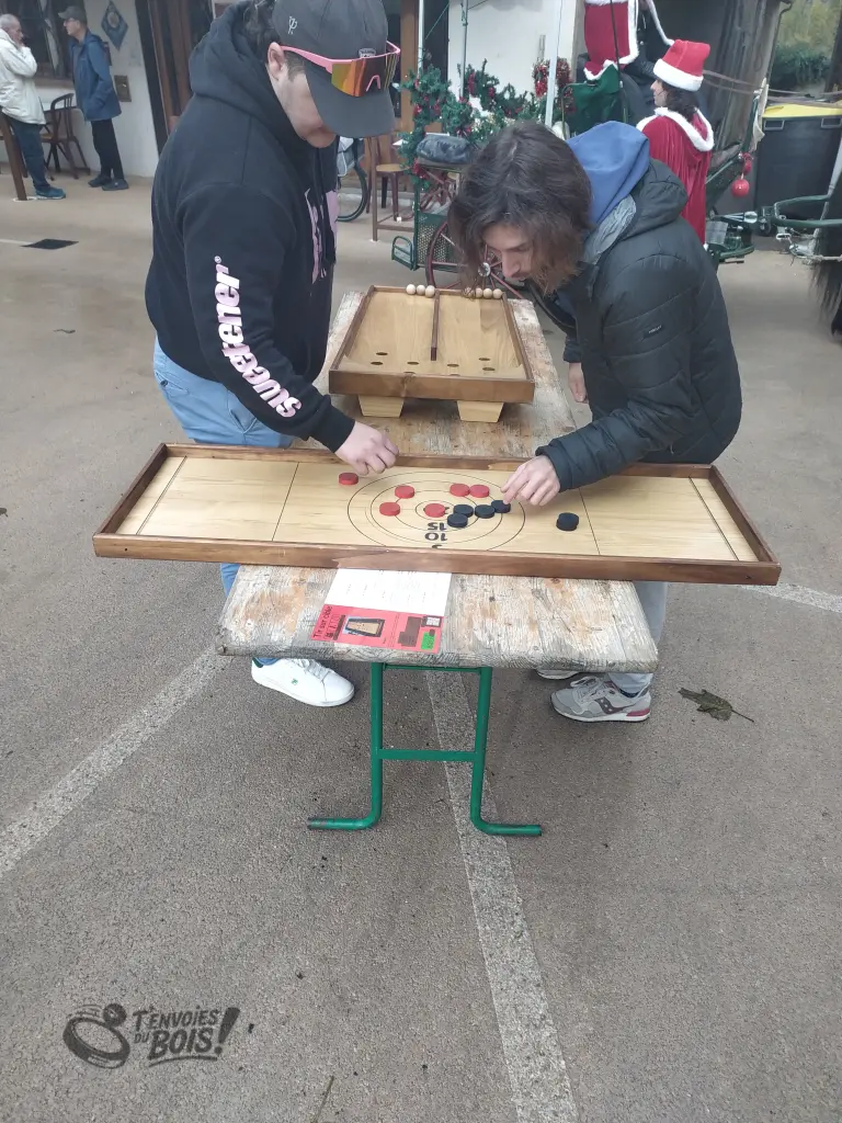 Des amis comptent les points après une partie de tir sur cible. Ils sont très concentrés, la partie est disputée. Photo prise lors du marché de Noël de Rieux-Volvestre en décembre 2025.