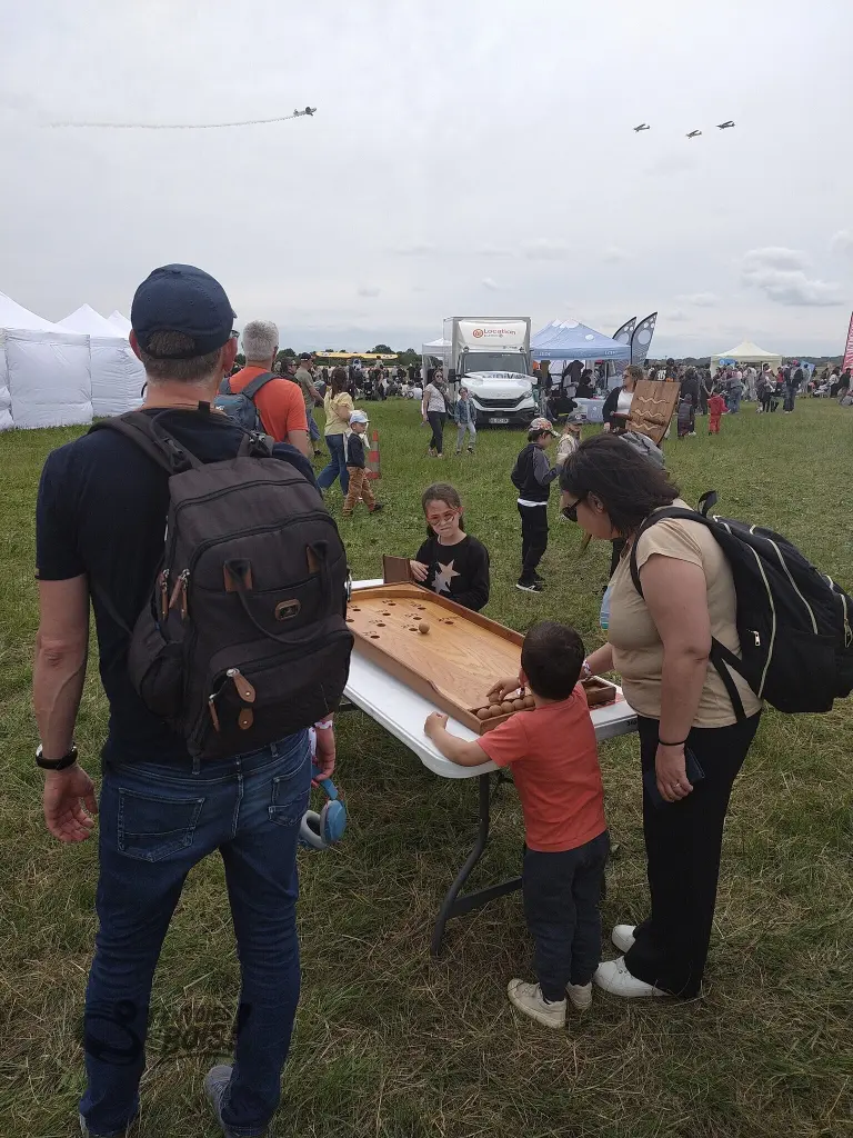 Un enfant joue au billard japonais, il ne prête absolument pas attention au ballet aérien qu'on peut voir en arrière-plan. Scène capturée lors du meeting aérien AirxExpo en mai 2026.