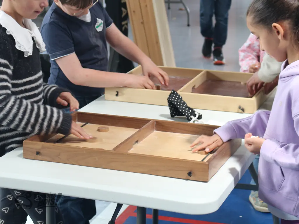 Un gros plan de deux passe-trappes en cours de partie. Les enfants adorent ce jeu en bois. Photo prise en 2025.