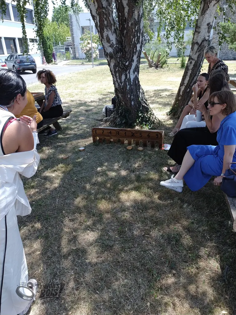 Une partie de troumadame dans un parc par une après-midi ensoleillée. À l'origine, ce jeu était pour les femmes aristocratiques, comme ici, où on peut voir que des femmes autour du jeu. Photo prise en juin 2026.